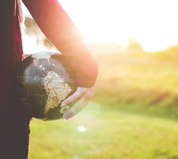 A person holding a globe in a sunlit field